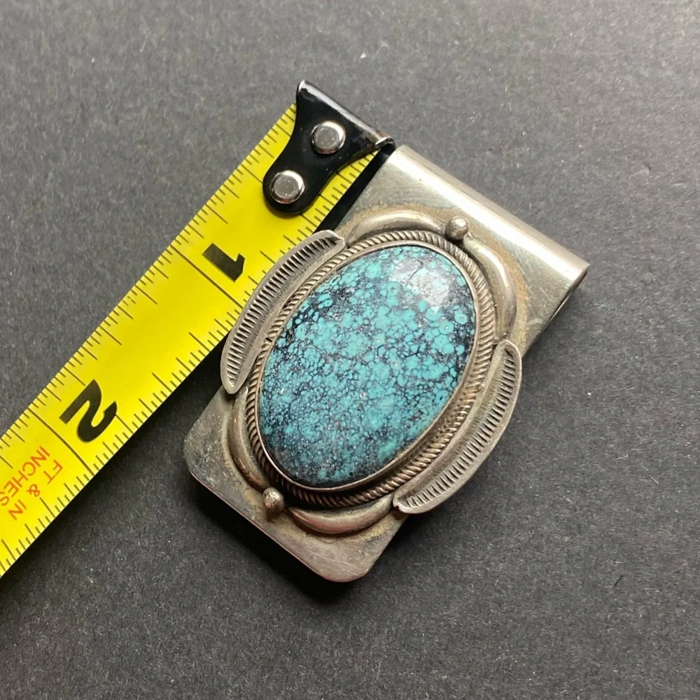 Silver toned money clip with polished blue stone. No stamps.
